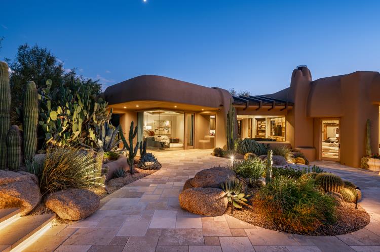 Warmly lit patios and glazed doors open toward the landscaped terrace.